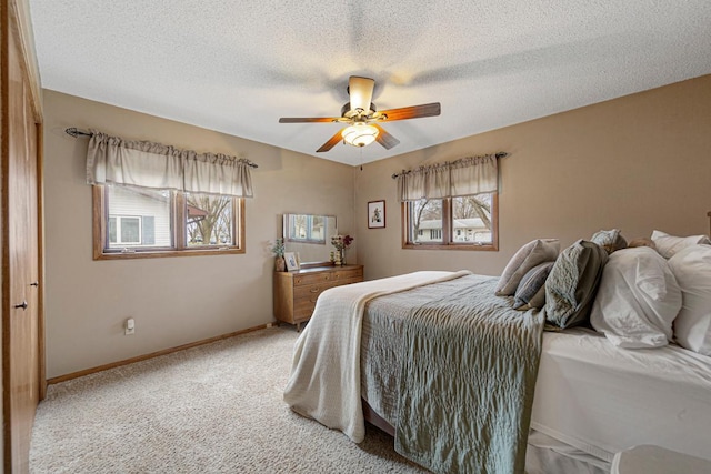 bedroom with baseboards, a textured ceiling, a ceiling fan, and light colored carpet
