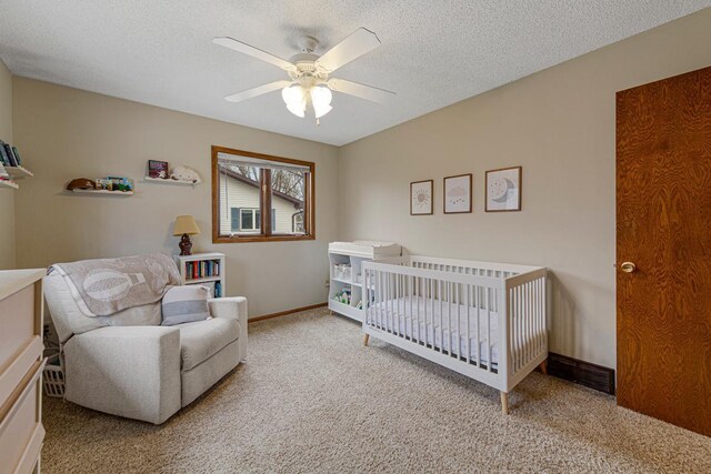 bedroom with carpet flooring, a textured ceiling, baseboards, ceiling fan, and a nursery area
