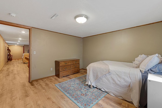 bedroom featuring baseboards, crown molding, and light wood-type flooring