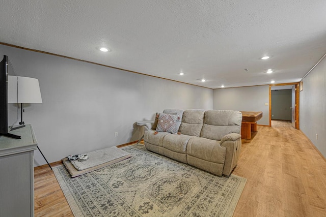 living room featuring light wood-style flooring, a textured ceiling, and recessed lighting