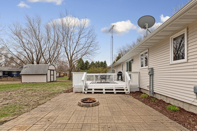 view of patio with a fire pit, an outdoor structure, a deck, and a storage shed