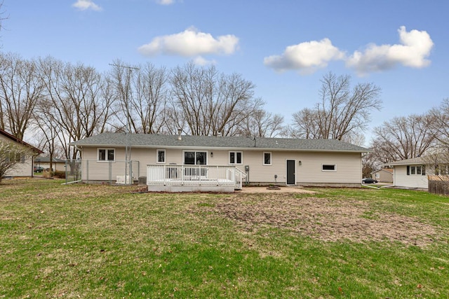 rear view of house with a wooden deck and a lawn