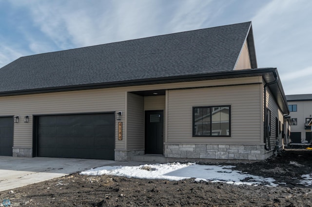 view of front of house with driveway, stone siding, and a garage