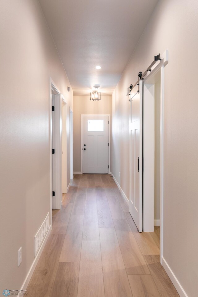 doorway featuring visible vents, baseboards, light wood-type flooring, and a barn door