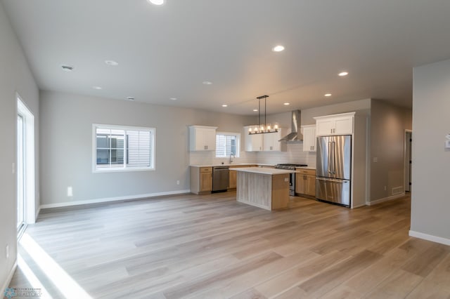 kitchen with stainless steel appliances, open floor plan, backsplash, and wall chimney range hood