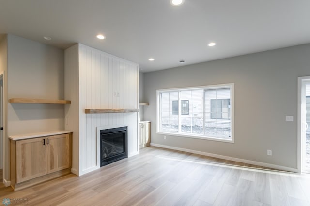 unfurnished living room with light wood finished floors, a fireplace, baseboards, and recessed lighting