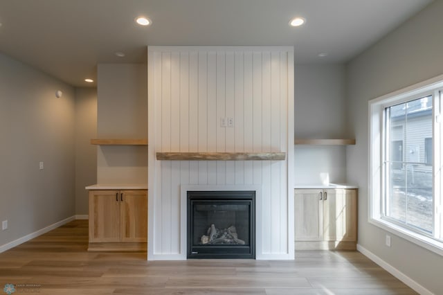 unfurnished living room with recessed lighting, light wood finished floors, a large fireplace, and baseboards