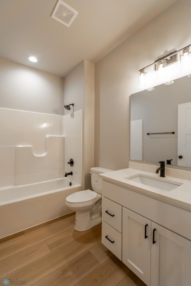 full bathroom featuring vanity, visible vents,  shower combination, toilet, and wood finished floors