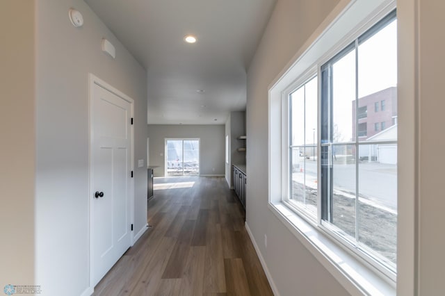 hall featuring baseboards, recessed lighting, and wood finished floors