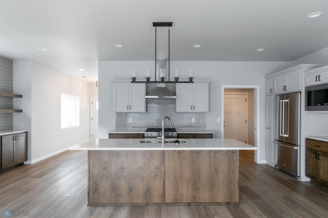 kitchen featuring a sink, light countertops, an island with sink, stainless steel appliances, and decorative backsplash