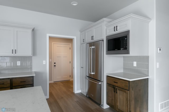 kitchen featuring dark wood finished floors, white cabinetry, visible vents, appliances with stainless steel finishes, and backsplash