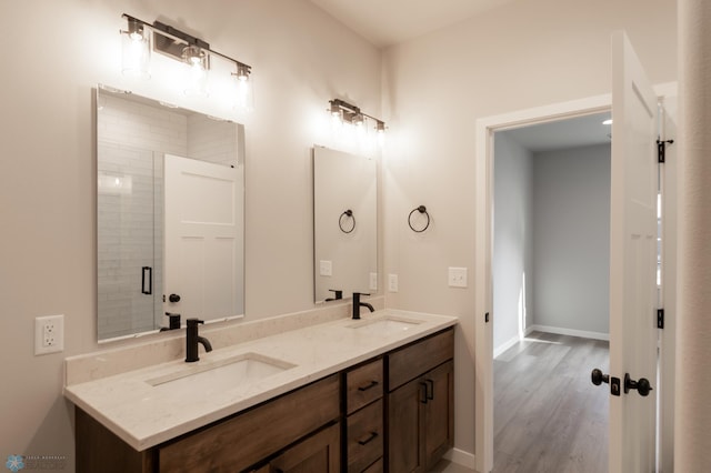 bathroom featuring double vanity, baseboards, a sink, and wood finished floors