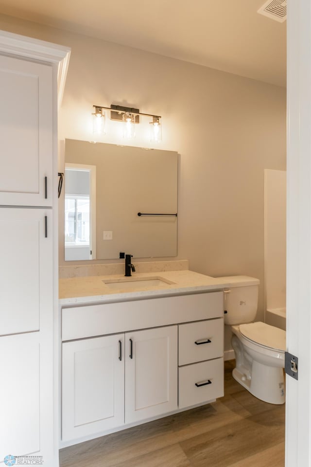 bathroom featuring vanity, visible vents, toilet, and wood finished floors