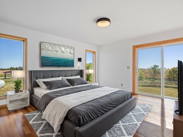 bedroom featuring hardwood / wood-style floors, access to exterior, and multiple windows