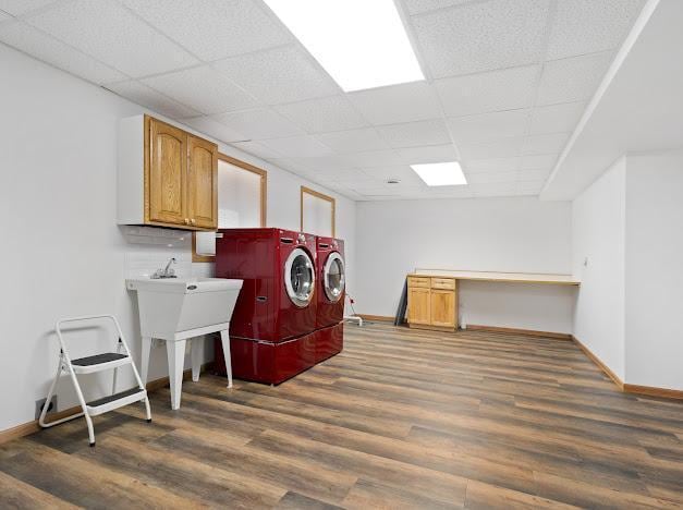 clothes washing area with baseboards, washer and clothes dryer, wood finished floors, and cabinet space