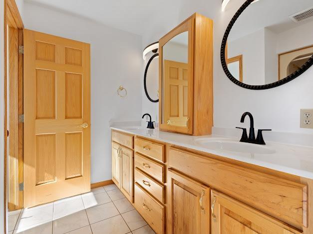 full bath featuring tile patterned floors, double vanity, a sink, and visible vents