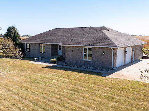 single story home featuring roof with shingles, driveway, a front yard, and a garage
