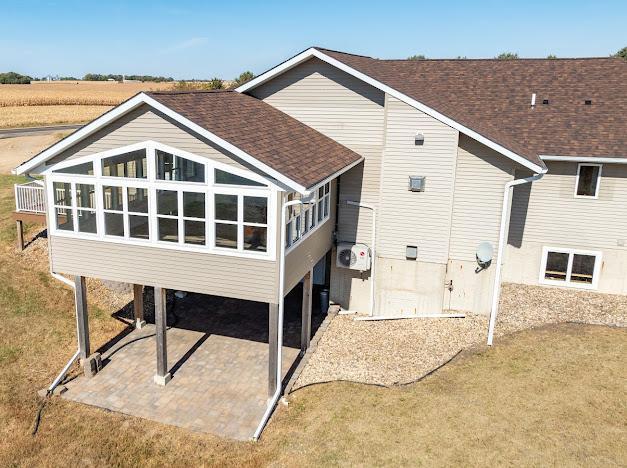 rear view of house with a patio area, a shingled roof, and a sunroom