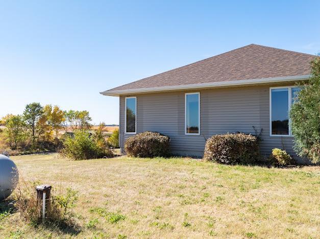 view of side of home with a yard and a shingled roof