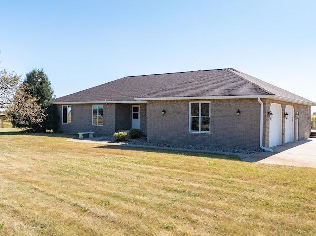 view of front facade featuring concrete driveway, a front yard, brick siding, and an attached garage
