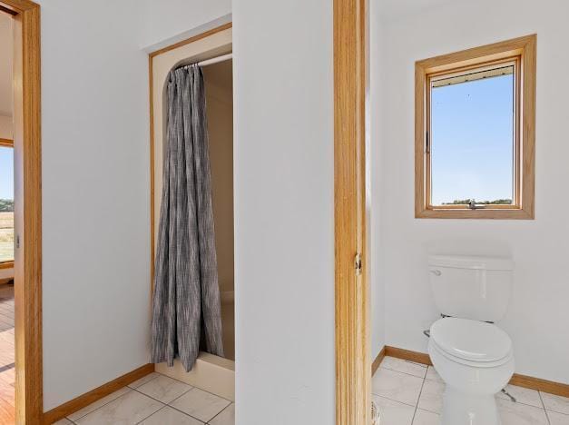 bathroom featuring toilet, tile patterned floors, a shower with shower curtain, and baseboards