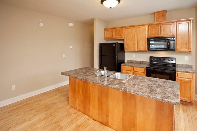 697 Cook Ave E, Saint Paul, MN 55106 - kitchen with black appliances, a sink, light wood-type flooring, baseboards, and a kitchen island with sink