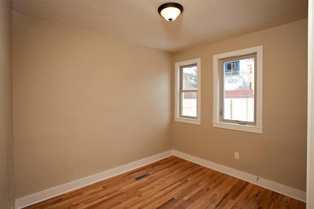697 Cook Ave E, Saint Paul, MN 55106 - unfurnished room featuring baseboards, light wood finished floors, and a textured ceiling