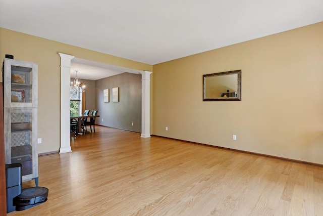 20413 Everton Trl N, Forest Lake, MN 55025 - unfurnished room with light wood finished floors, ornate columns, and an inviting chandelier