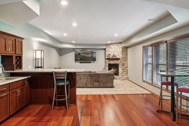 20413 Everton Trl N, Forest Lake, MN 55025 - kitchen featuring baseboards, a stone fireplace, a kitchen breakfast bar, recessed lighting, and wood finished floors