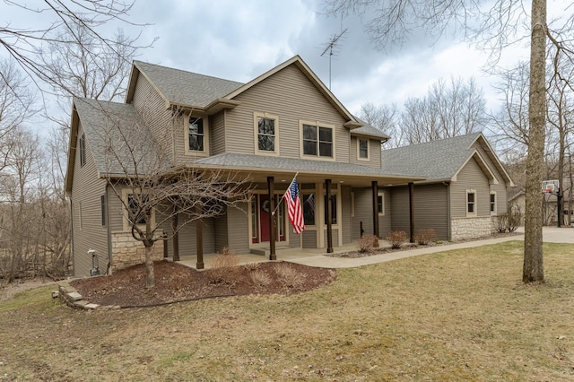 view of front facade featuring roof with shingles, covered porch, and a front yard