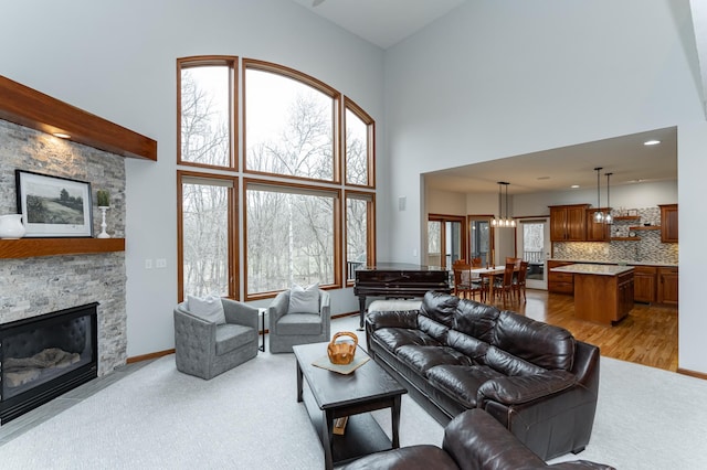 1125 Riverwood Dr SW, Oronoco, MN 55960 - carpeted living room with a towering ceiling, a stone fireplace, a chandelier, and baseboards