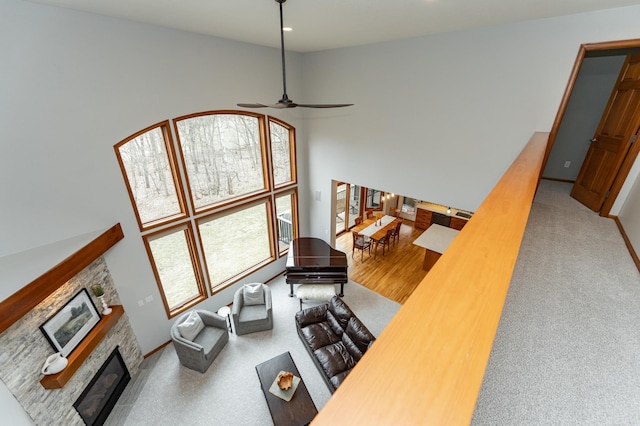 1125 Riverwood Dr SW, Oronoco, MN 55960 - living room featuring a glass covered fireplace, a ceiling fan, a towering ceiling, baseboards, and carpet floors