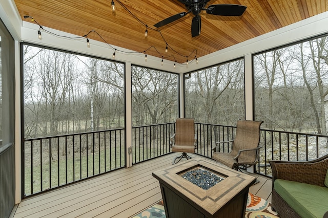 1125 Riverwood Dr SW, Oronoco, MN 55960 - sunroom with an outdoor fire pit, a ceiling fan, wood ceiling, a wooden deck, and a view of trees