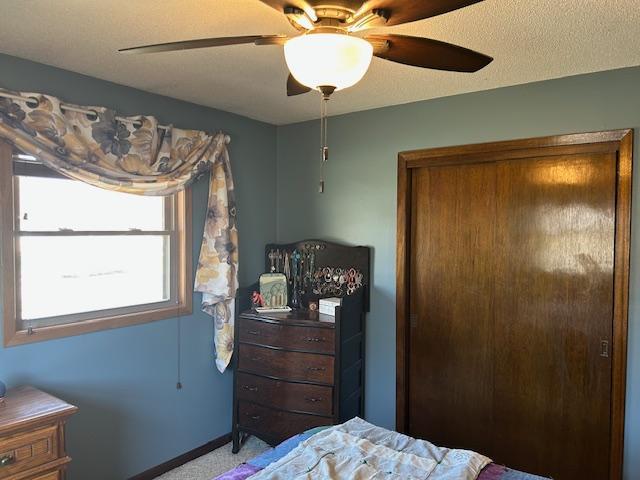 carpeted bedroom with ceiling fan and baseboards
