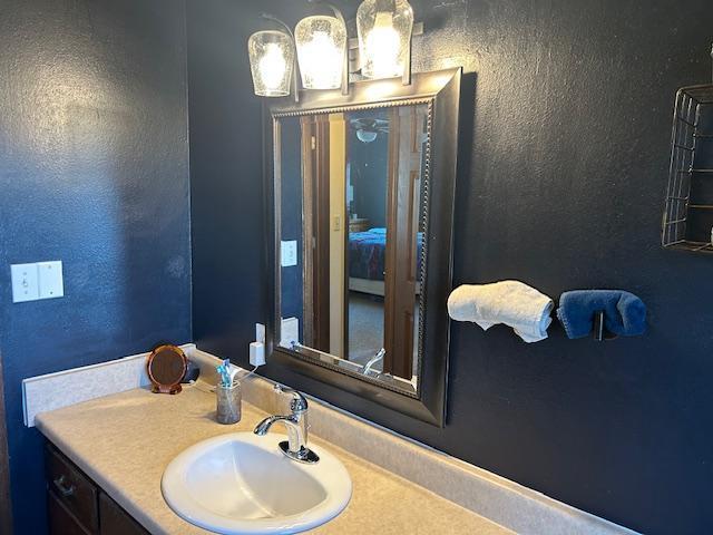 bathroom with connected bathroom, a textured wall, and vanity