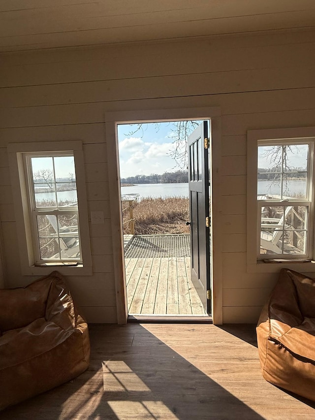 doorway to outside with wood finished floors, wooden walls, and a water view