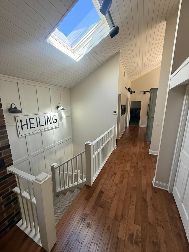 hall with vaulted ceiling with skylight, baseboards, wood ceiling, and hardwood / wood-style flooring