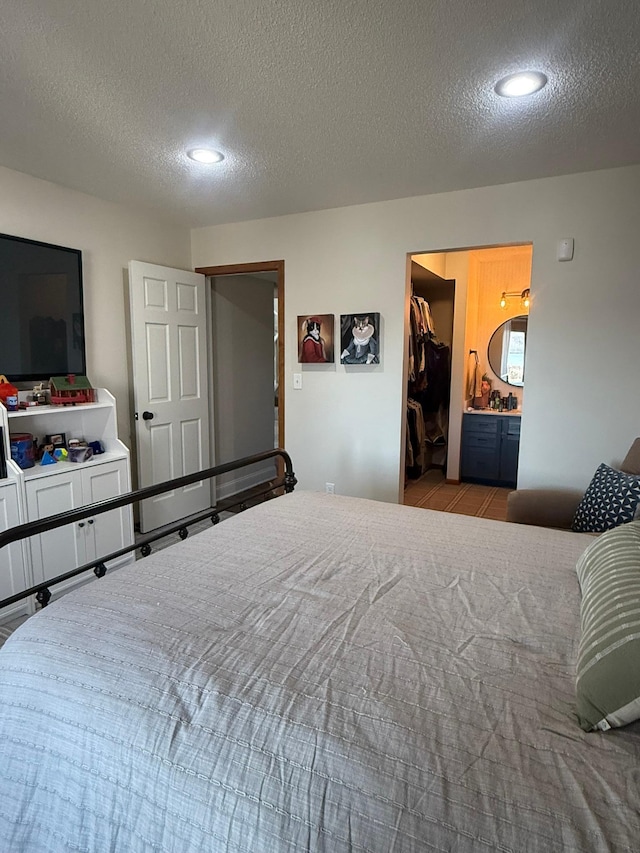 bedroom featuring a spacious closet, a textured ceiling, and recessed lighting