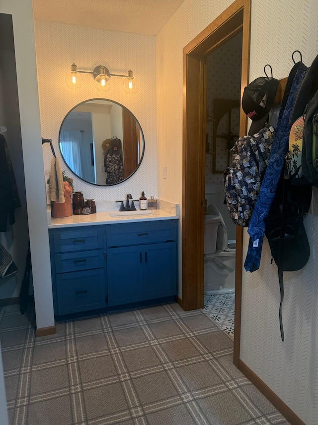 bathroom featuring vanity and wallpapered walls