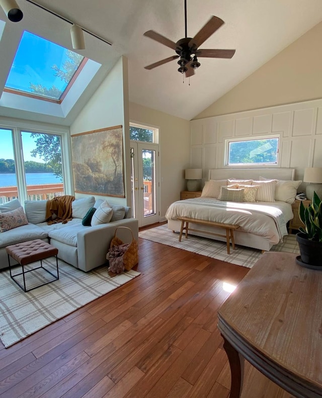 bedroom with hardwood / wood-style flooring, access to outside, a water view, and a skylight