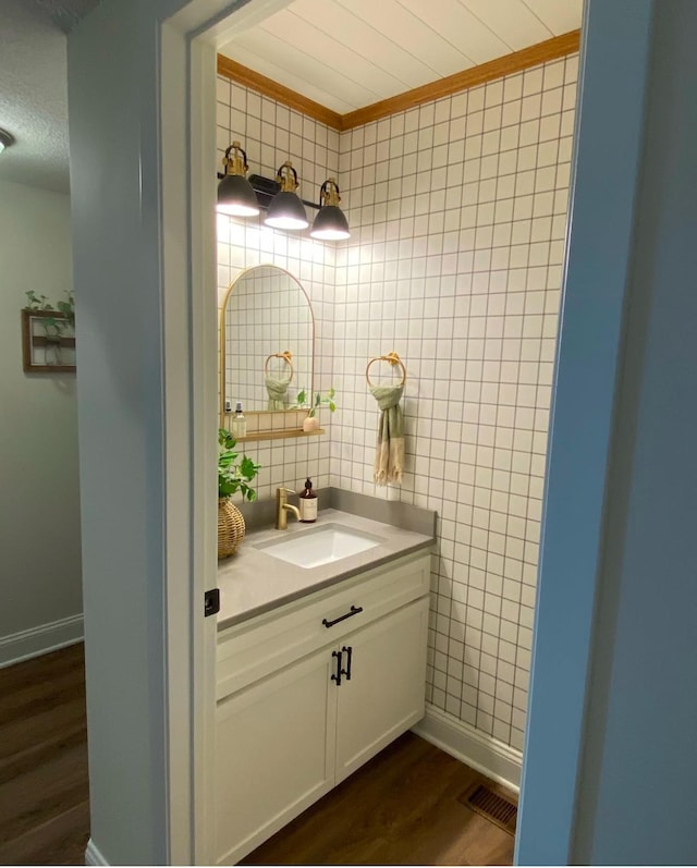 bathroom with a textured ceiling, tile walls, visible vents, wood finished floors, and vanity