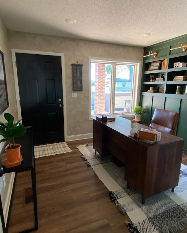 home office featuring dark wood finished floors, a textured ceiling, and baseboards