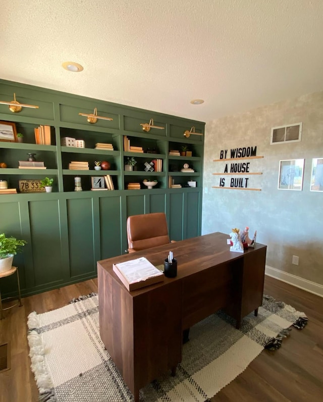 office space with baseboards, wood finished floors, visible vents, and a textured ceiling