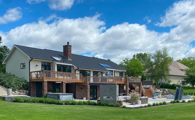 rear view of house with a chimney, a wooden deck, brick siding, a hot tub, and a patio