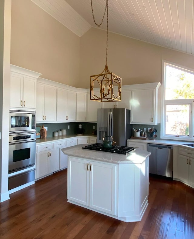kitchen with high vaulted ceiling, a center island, a warming drawer, an inviting chandelier, and appliances with stainless steel finishes