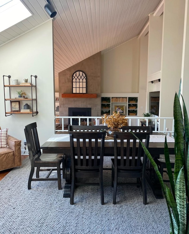 dining area with wooden ceiling, a fireplace, and high vaulted ceiling