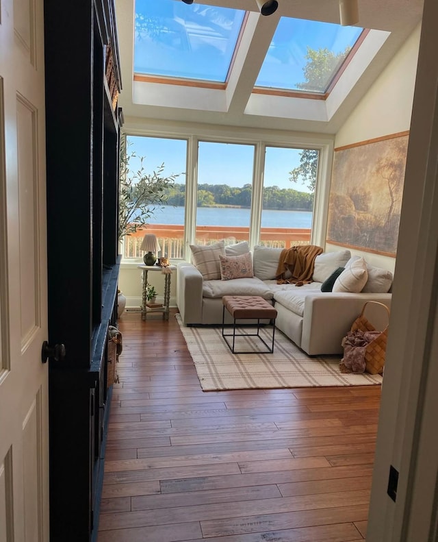 living area featuring hardwood / wood-style flooring, a wealth of natural light, a water view, and a skylight