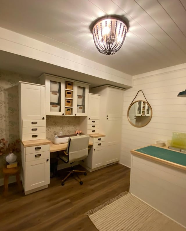 office space featuring built in study area, an inviting chandelier, dark wood-style flooring, and wallpapered walls