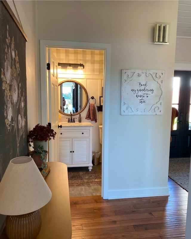 hall with baseboards, hardwood / wood-style floors, and a sink