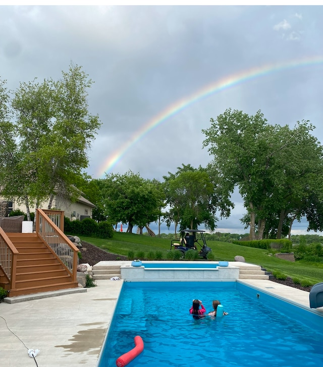 outdoor pool featuring a yard and stairs